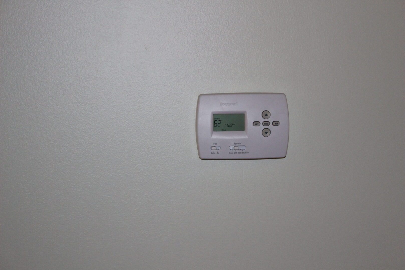 A white digital thermostat mounted on the wall.