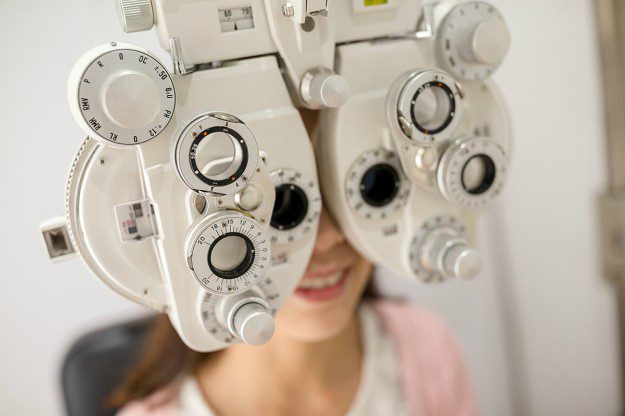 A woman is looking through the lens of an eye test.